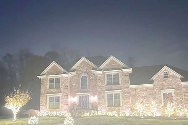 Wrapped mini Christmas trees and lit bushes at a colonial home entry in Barbourmeade, Kentucky
