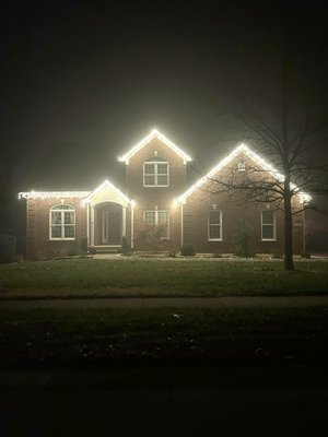 Christmas lights outlining a brick two-story home at dusk in Middletown, Kentucky